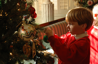 Charleston Catholic School first-grader Brendan Elliott places an ornament on Bishop Robert E. Guglielmone’s Christmas tree Dec. 10. The class won a party at the bishop’s house for collecting the most pounds of food for local food pantries.