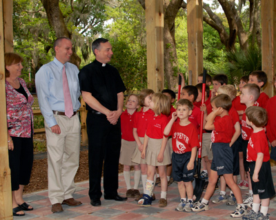 Second-grade teacher Bonnie Goltz, Principal Chris Trott, and Father Timothy D. Tebalt, administrator of St. Peter Church, speak to students in the new outdoor classroom at St. Peter School in Beaufort April 19.