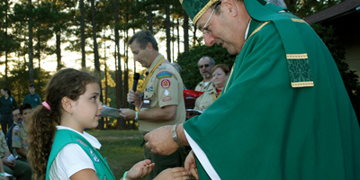 (Miscellany/Christina Lee Knauss) A Girl Scout is presented with her award by Bishop Robert E. Guglielmone at the sixth annual Catholic Scout Camporee held at Lake Weston recently. In the background at center is Jim Weiskircher, chairman of the diocesan Catholic Committee on Scouting.