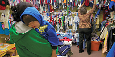 (Miscellany/Keith Jacobs) Joanne Bennett sorts through clothing for Alisha Lopez and her child, Angel, at the Pee Dee Catholic Charities Office in Conway. The Bishop’s Stewardship Appeal increased funding to all Catholic Charities bureaus this year due to rising demand for services.