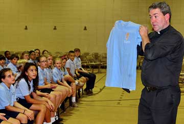 Father Jeffrey Kirby holds up a vocations club shirt.