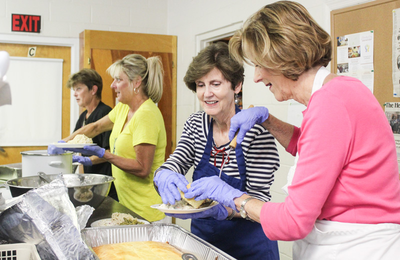 Linda Neely (left) and Gail Stafford put cornbread on a plate for a client at the Dorothy Day Soup Kitchen in Rock Hill.