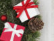 Christmas side border of red and white gifts and tree branches on a white wood background